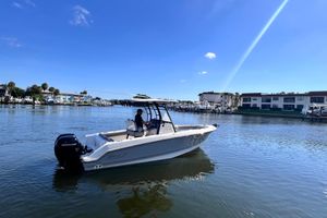 Boston Whaler 230 Outrage 2023 Boston Whaler 230 Outrage boat on calm water, under clear blue sky.