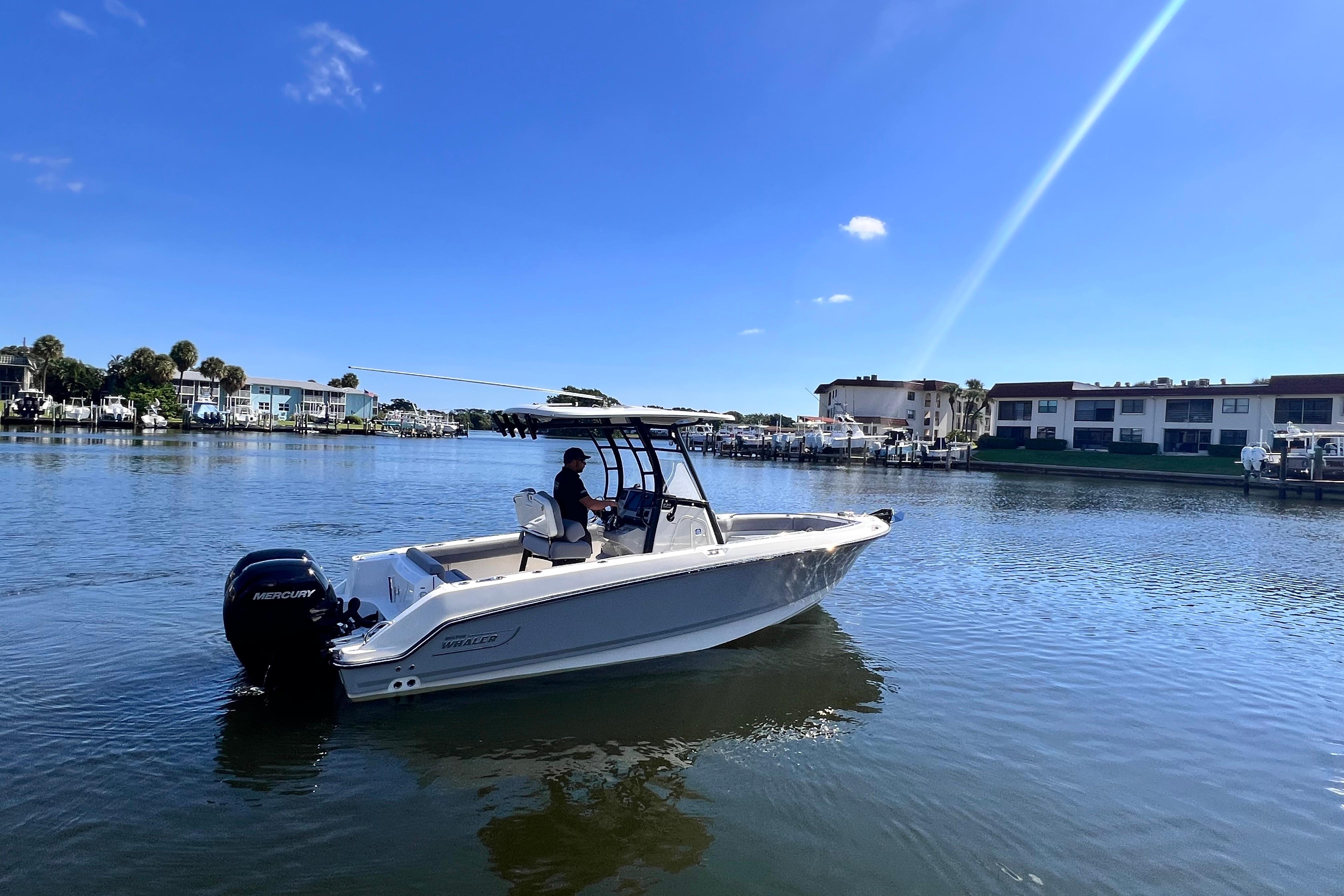 Boston Whaler 230 Outrage 2023 Boston Whaler 230 Outrage boat on calm water, under clear blue sky.