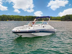 Four Winns F224 2008 Four Winns F224 boat on a lake under a blue sky with clouds.