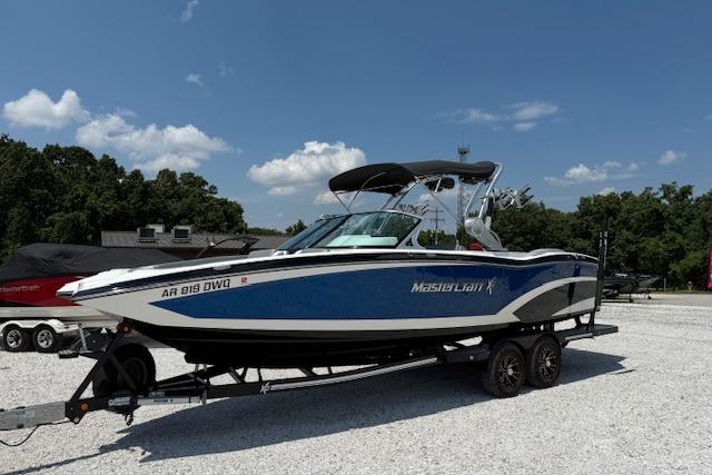 MasterCraft X26 2016 MasterCraft X26 boat on trailer, blue and white, parked outdoors.