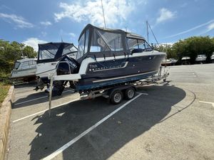 Jeanneau Merry Fisher 695 2018 Jeanneau Merry Fisher 695 boat on trailer in parking lot under blue sky.