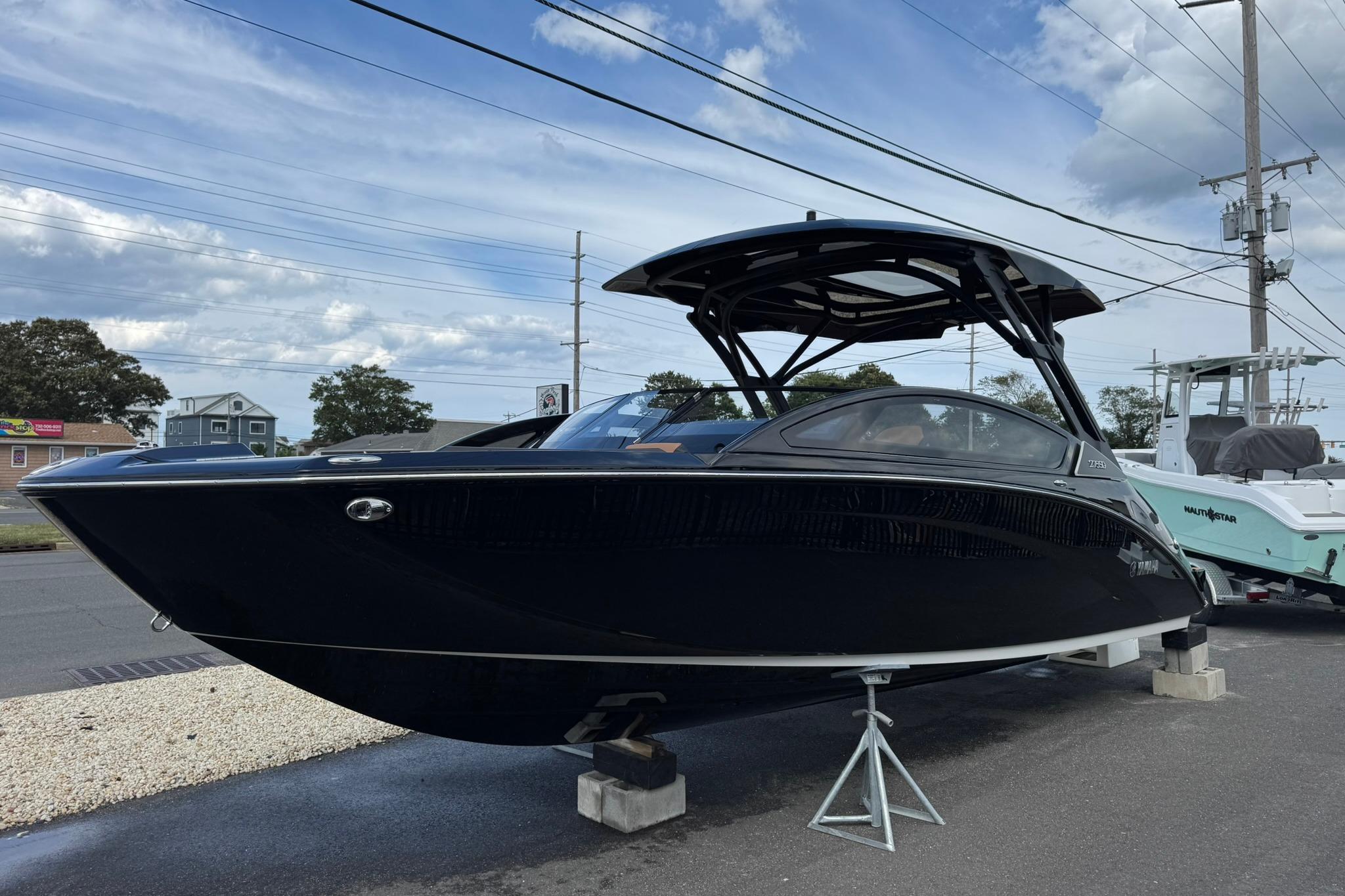 Yamaha Boats 275SD 2026 Yamaha Boats 275SD displayed outdoors on a stand under a cloudy sky.