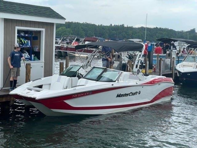 MasterCraft X24 2021 MasterCraft X24 boat docked at a marina, featuring a sleek red and white design.