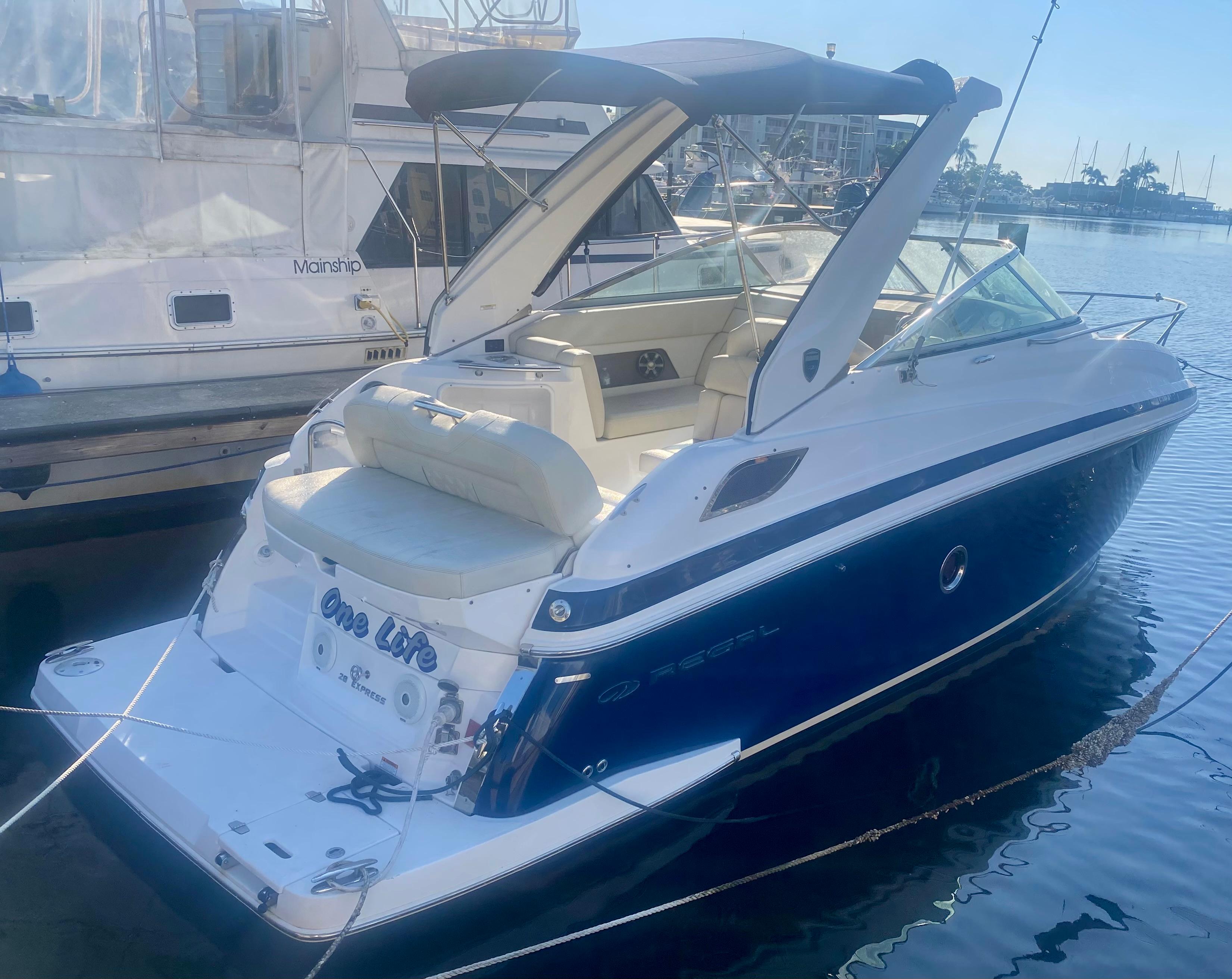 Regal 28 Express 2018 Regal 28 Express boat docked, featuring sleek design and spacious seating.
