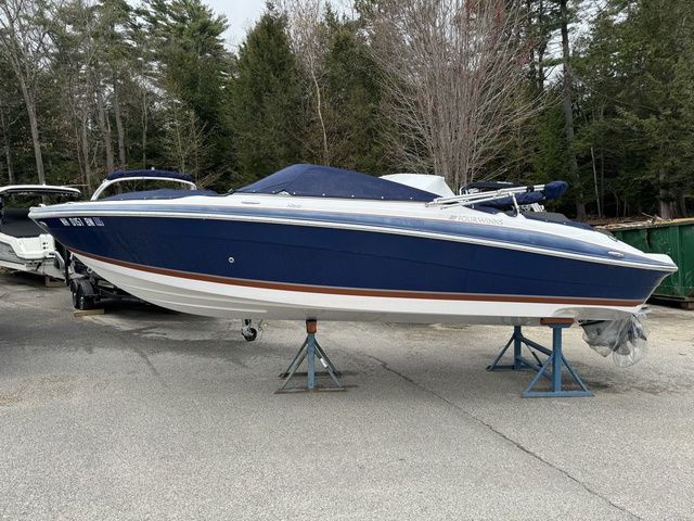 Four Winns H210 2008 Four Winns H210 boat in blue, elevated on stands, surrounded by trees.