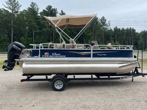 Sun Tracker Bass Buggy 18 DLX 2025 Sun Tracker Bass Buggy 18 DLX pontoon boat on trailer, with canopy, in outdoor setting.