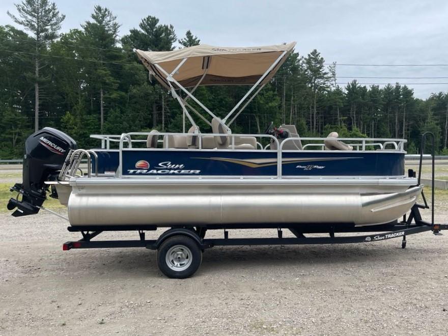 Sun Tracker Bass Buggy 18 DLX 2025 Sun Tracker Bass Buggy 18 DLX pontoon boat on trailer, with canopy, in outdoor setting.