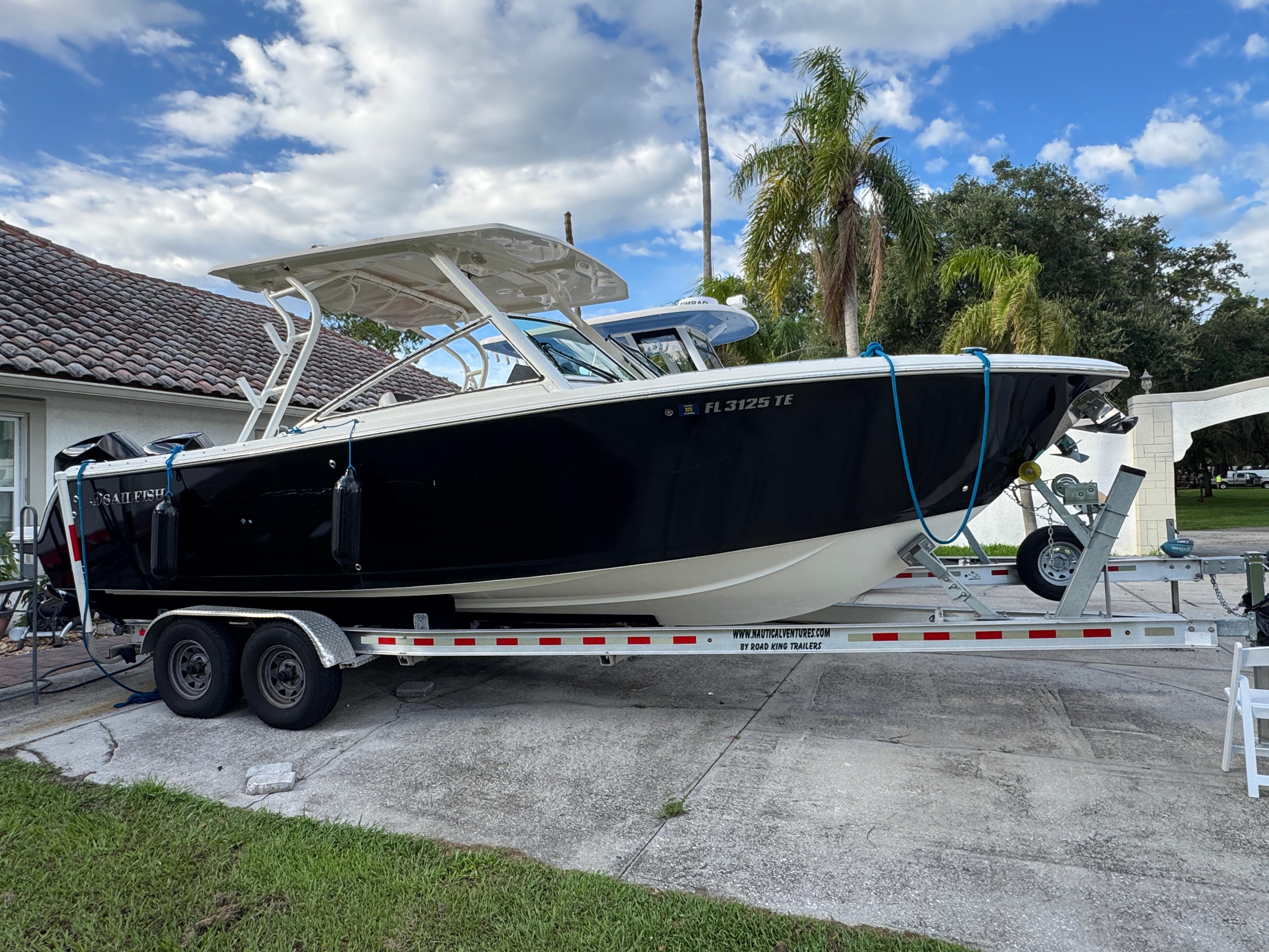 Sailfish 276 DC 2022 Sailfish 276 DC boat on trailer, parked in driveway with palm trees.