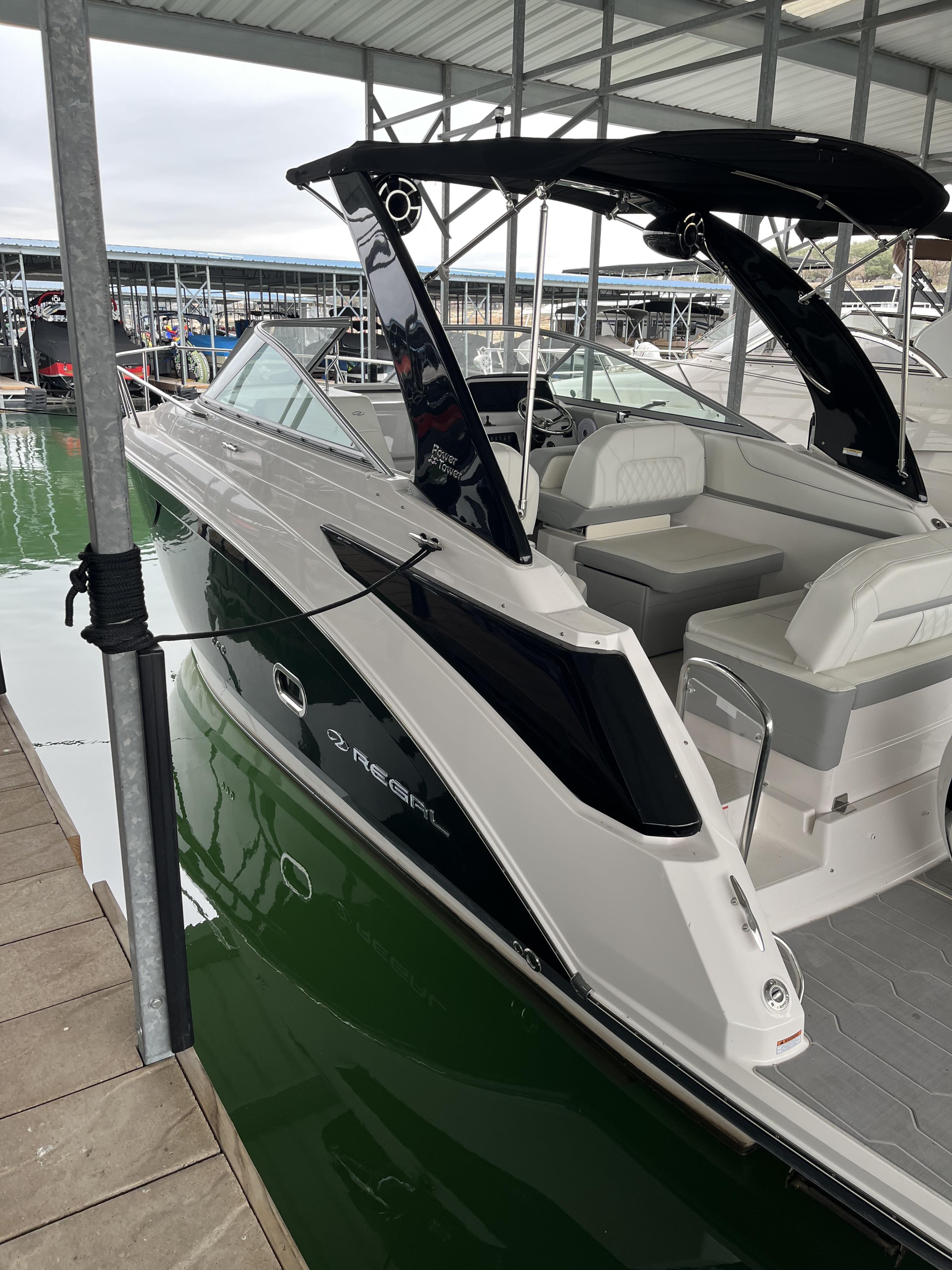 Regal 26XO 2022 Regal 26XO boat docked in marina, featuring sleek design and comfortable seating.