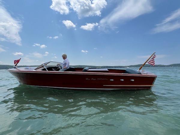 Chris-Craft 23 Continental 1956 Chris-Craft 23 Continental boat on water, clear sky, American flag waving.