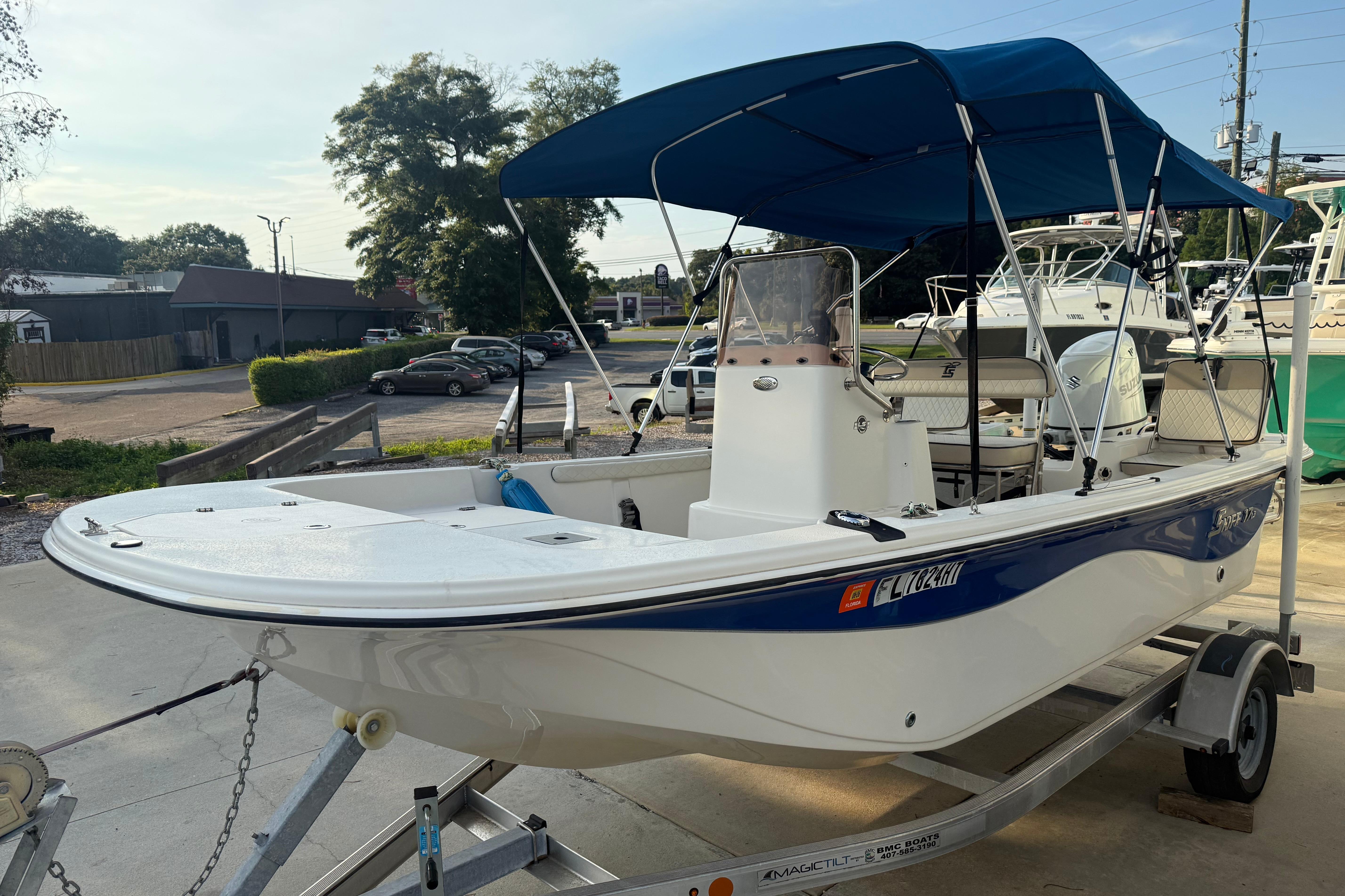Carolina Skiff 17 LS 2022 Carolina Skiff 17 LS boat with blue canopy on a trailer in a parking lot.