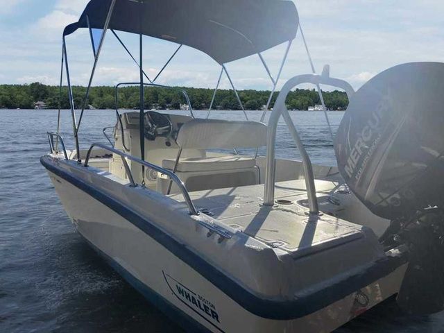 Boston Whaler 180 Dauntless 2015 Boston Whaler 180 Dauntless boat with canopy on a calm lake.