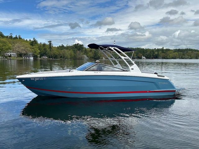 Cobalt R8 2025 Cobalt R8 boat on a serene lake with lush green shoreline.
