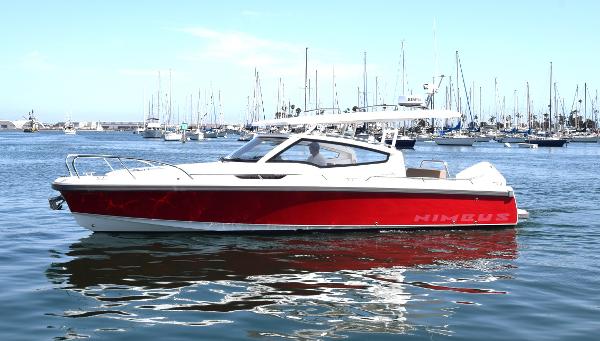 Nimbus W9 2024 Nimbus W9 boat in marina, red and white design, calm water, clear sky.