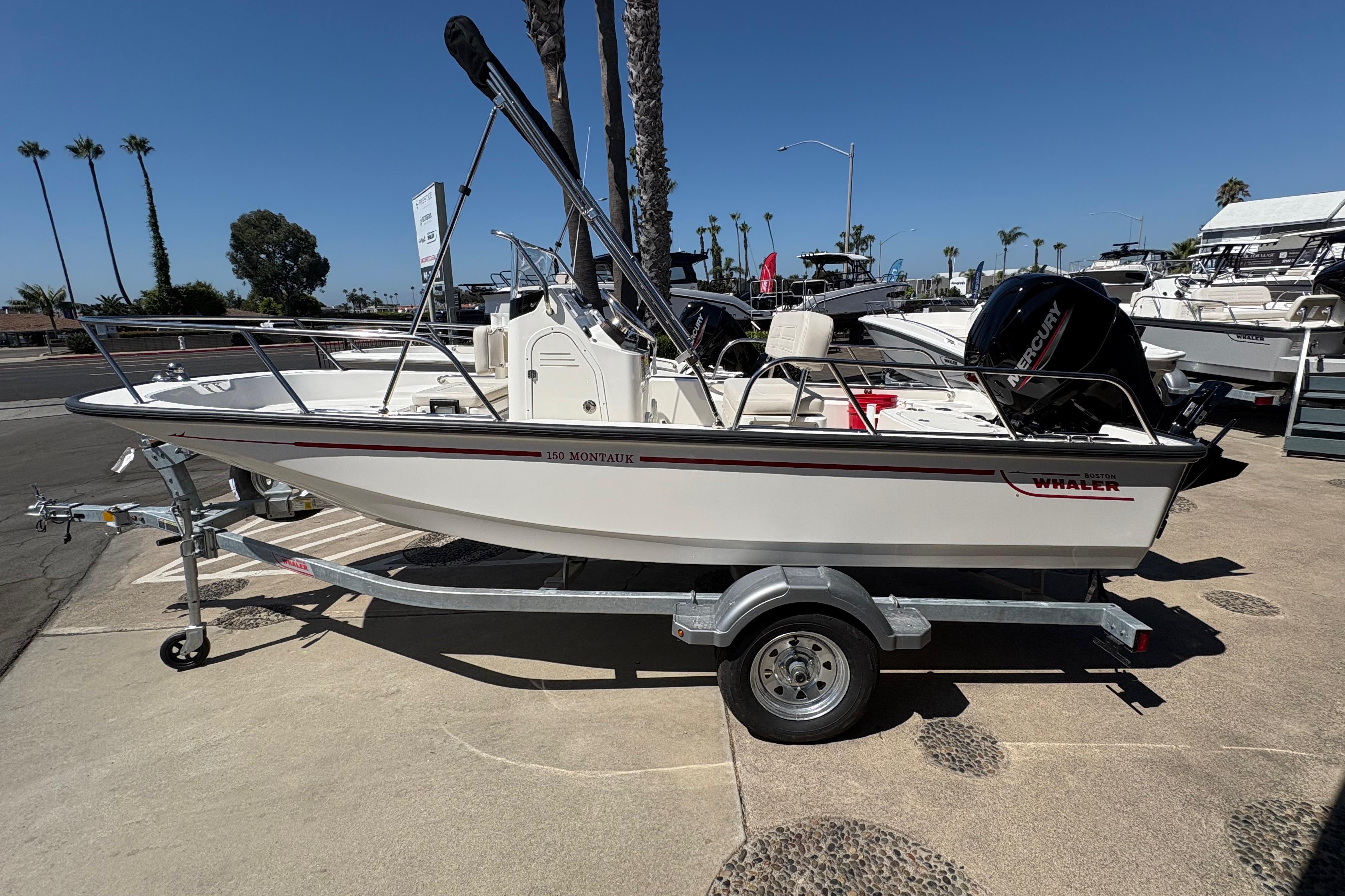 Boston Whaler 150 Montauk 2026 Boston Whaler 150 Montauk boat on trailer, parked outdoors under clear blue sky.