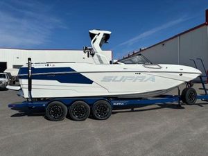 Supra SE 575 2025 Supra SE 575 boat on trailer, white and blue design, parked outdoors.