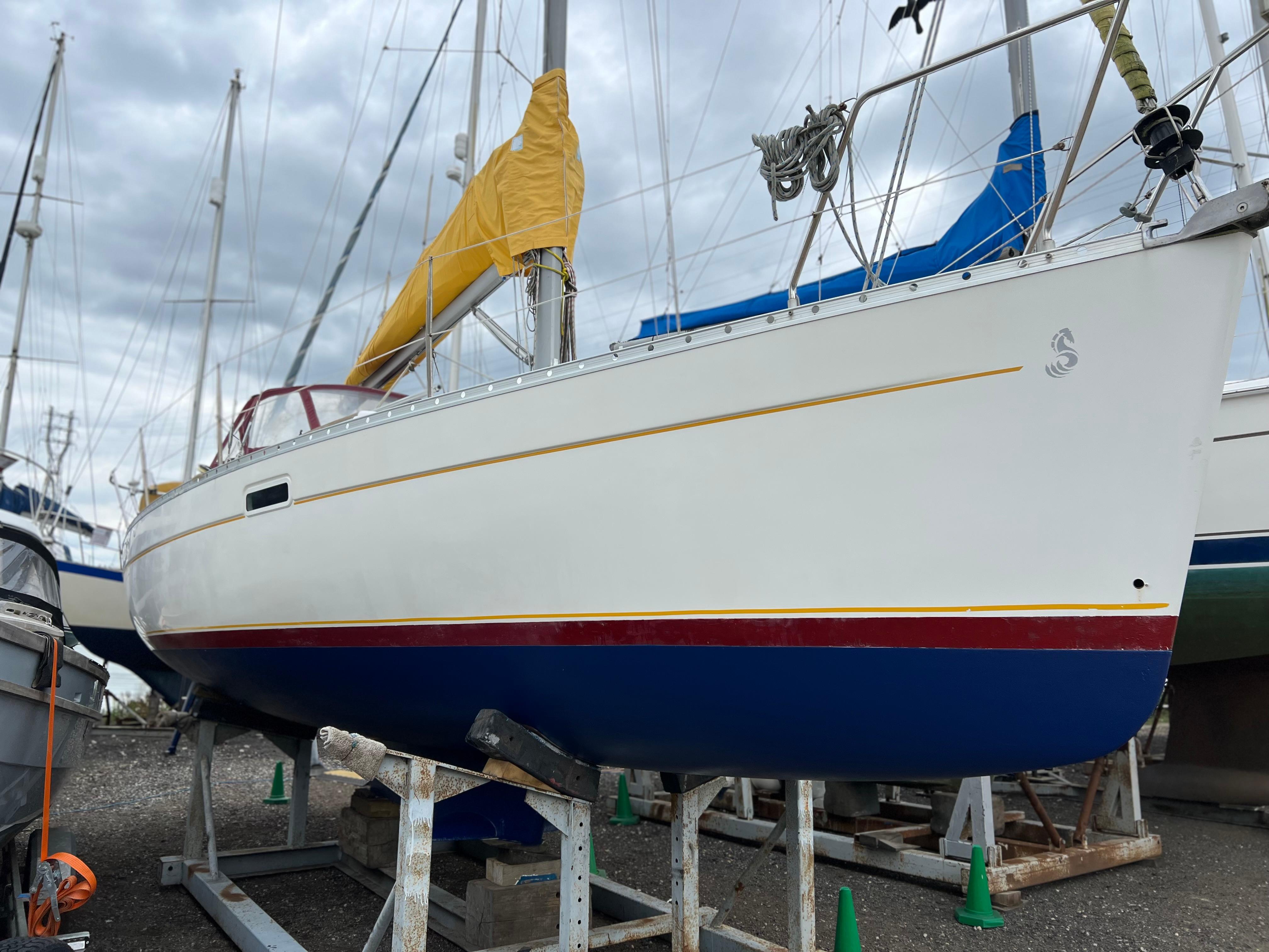 Beneteau Oceanis Clipper 311 2000 Beneteau Oceanis Clipper 311 sailboat on dry dock, featuring a blue hull and yellow sail cover.