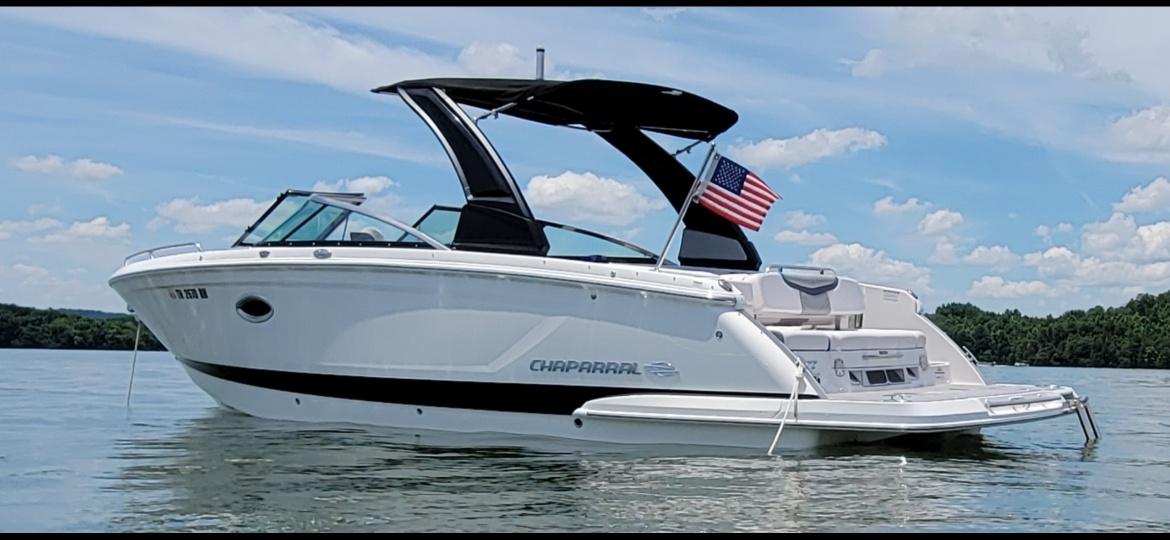 Chaparral 267 SSX 2018 Chaparral 267 SSX boat on water, American flag, clear sky, scenic background.