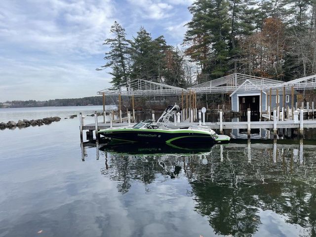 MasterCraft X46 - NEW TRANY 2015 MasterCraft X46 boat docked on a serene lake with trees and boathouse.