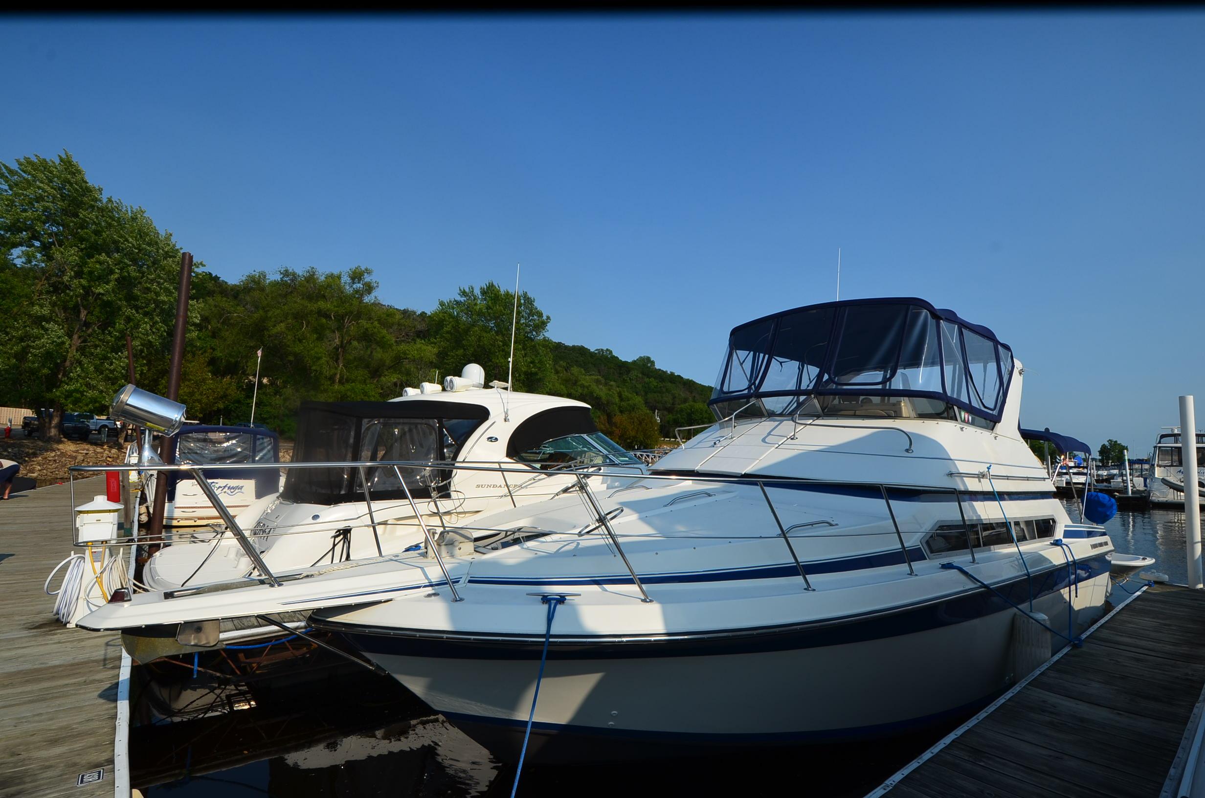 Carver Santego 1989 Carver SANTEGO yacht docked at a marina, surrounded by trees and clear blue sky.