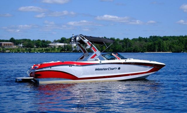 MasterCraft X24 2023 MasterCraft X24 boat on a lake, featuring sleek red and white design.