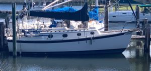 Com-Pac 27/2 1989 Com-Pac 27/2 sailboat docked in a marina, featuring a blue cover and calm waters.