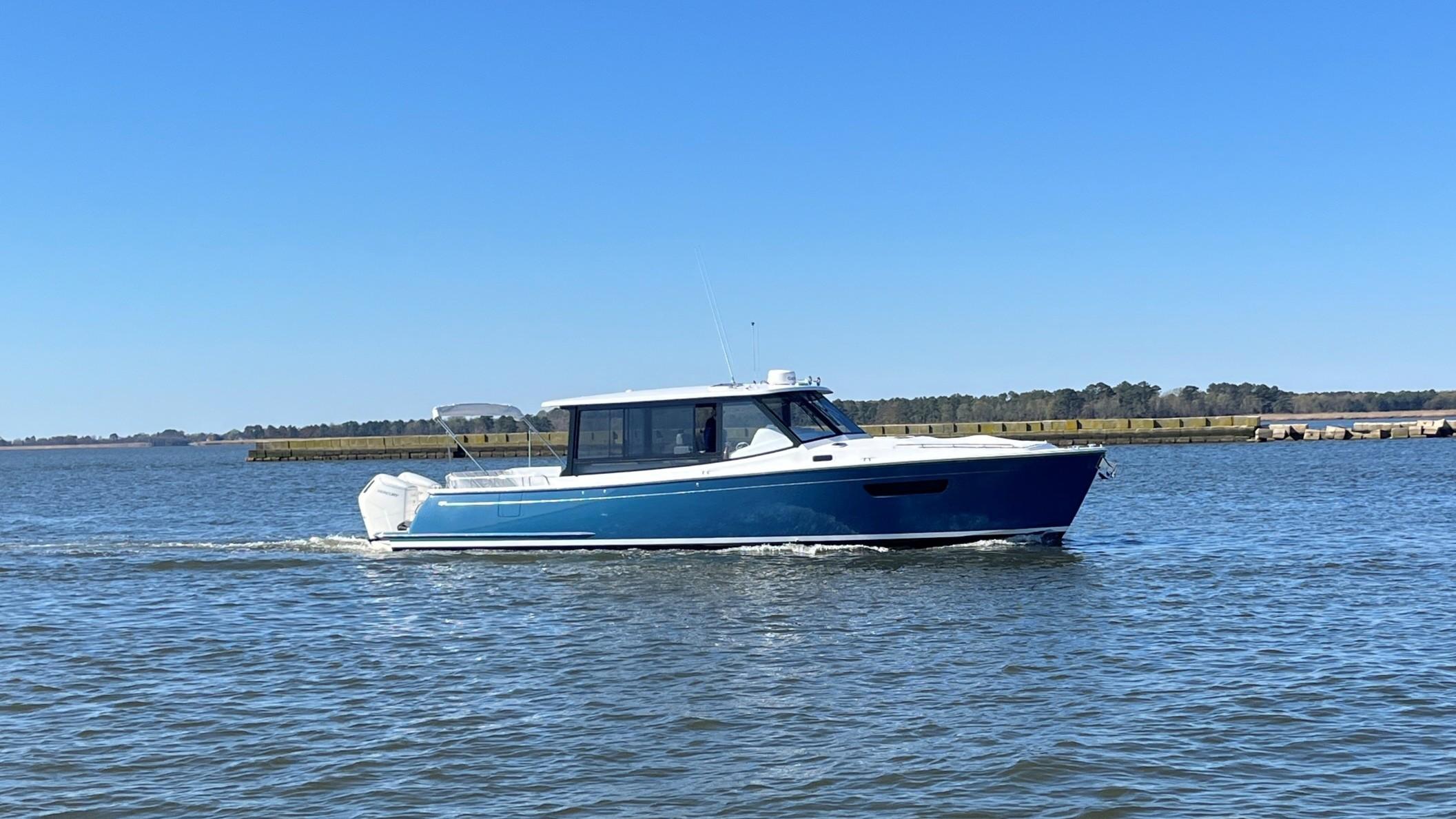 MJM 4 2025 MJM 4 boat cruising on a calm lake under a clear blue sky.