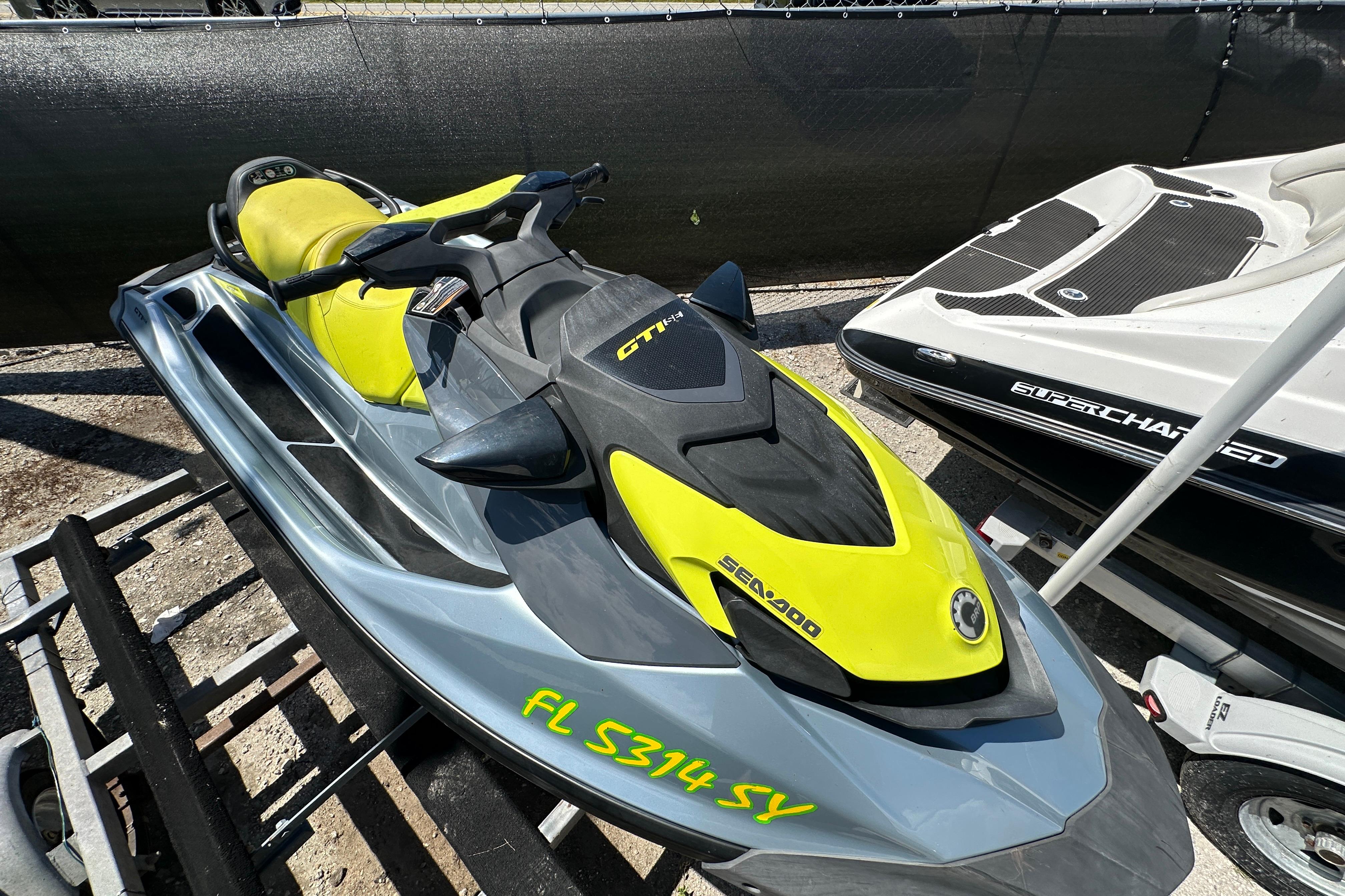 Sea-Doo GTI SE 130 2021 Sea-Doo GTI SE 130 jet ski in vibrant yellow and gray, parked on a trailer.