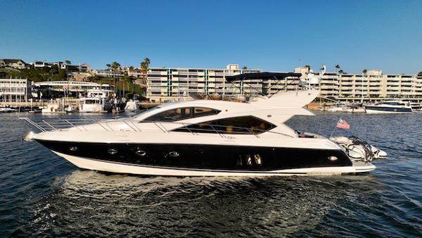 Sunseeker Manhattan 60 Co Ownership 2008 Sunseeker Manhattan 60 yacht cruising in a marina with modern buildings in the background.