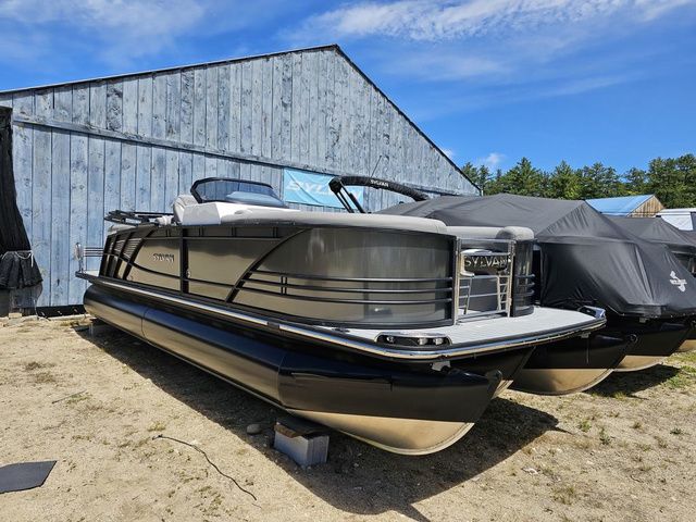 Sylvan S3 LZ 2023 Sylvan S3 LZ pontoon boat parked outdoors near a wooden building.