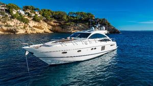 Princess V65 Luxury 2007 Princess V65 yacht anchored near scenic rocky coastline.