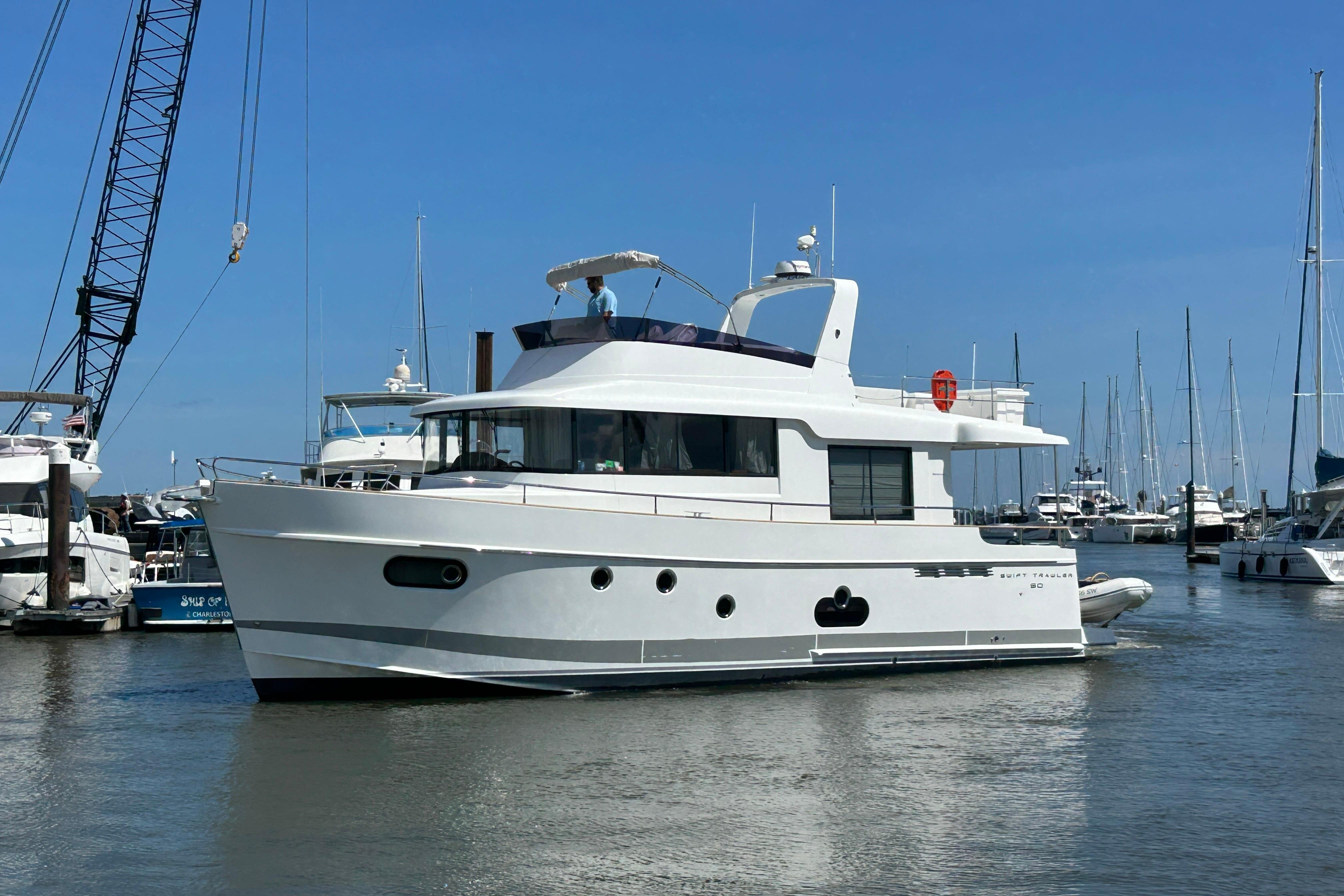 Beneteau Swift Trawler 50 2019 Beneteau Swift Trawler 50 yacht docked in a marina under clear blue skies.
