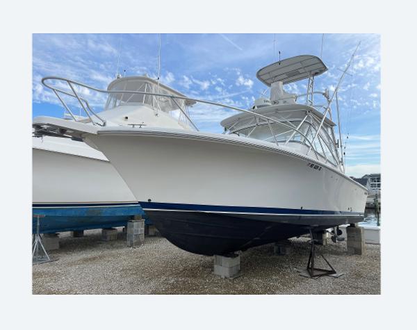 Luhrs 28 Open 2007 Luhrs 28 Open boat on dry dock, white hull, blue stripe, clear sky background.