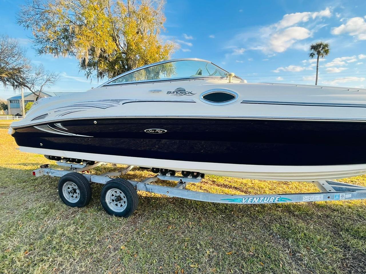 Sea Ray 240 Sundeck 2005 Sea Ray 240 Sundeck boat on trailer, parked on grass under blue sky.