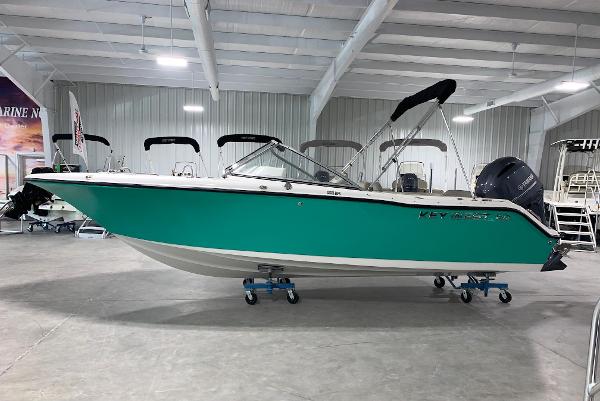 Key West 203 DFS 2024 Key West 203 DFS boat in showroom, teal hull, black canopy, outboard motor.