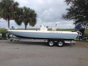 Skeeter SX240 2016 Skeeter 240SX boat on trailer with outboard motor, parked near palm trees.