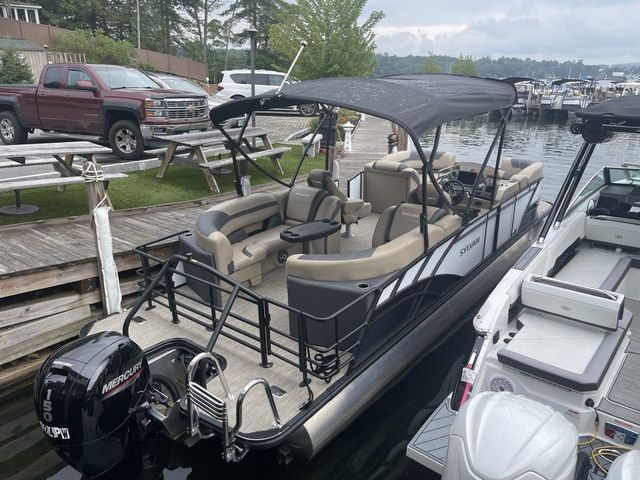 Sylvan L-3 LZ 2023 Sylvan L-3 LZ pontoon boat docked by a lakeside with canopy and Mercury outboard motor.
