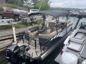 Sylvan L-3 LZ 2023 Sylvan L-3 LZ pontoon boat docked by a lakeside with canopy and Mercury outboard motor.