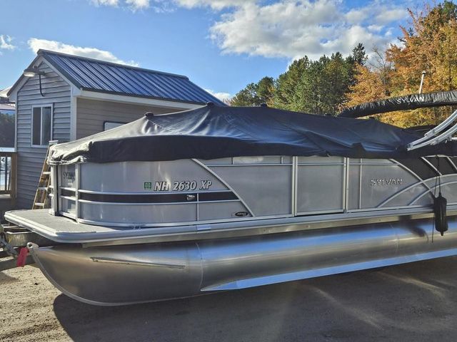 Sylvan 8524 Mirage LZ 2023 Sylvan 8524 Mirage LZ pontoon boat covered, parked near a house, under a blue sky.