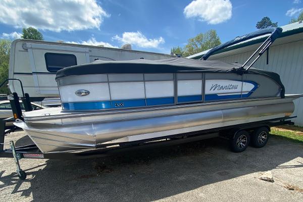Manitou 25 LX RFX 2024 Manitou 25 LX RFX pontoon boat on trailer, parked outdoors.