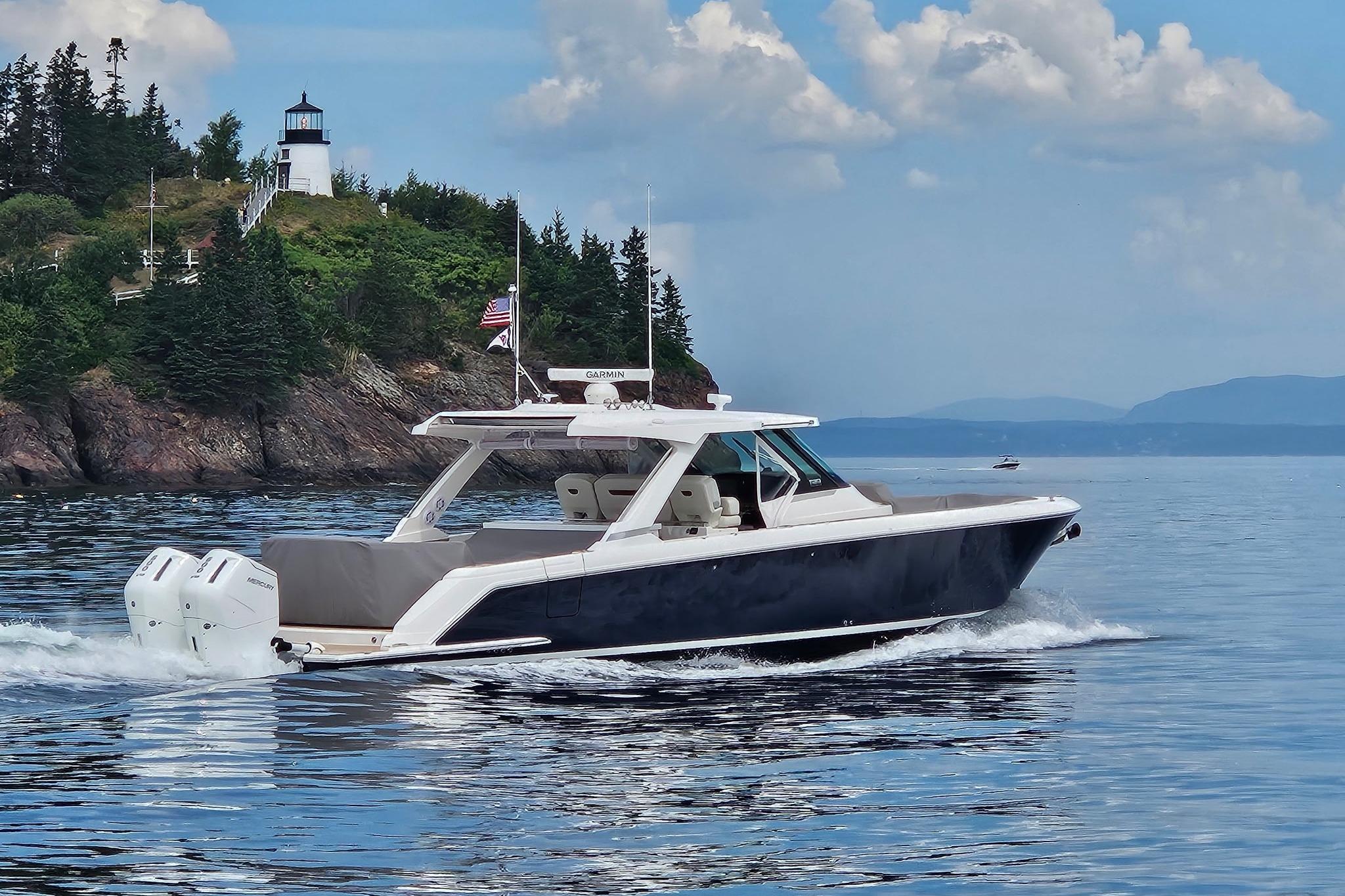 Tiara Yachts 43 LS 2024 Tiara Yachts 43 LS cruising near a scenic lighthouse and lush greenery.