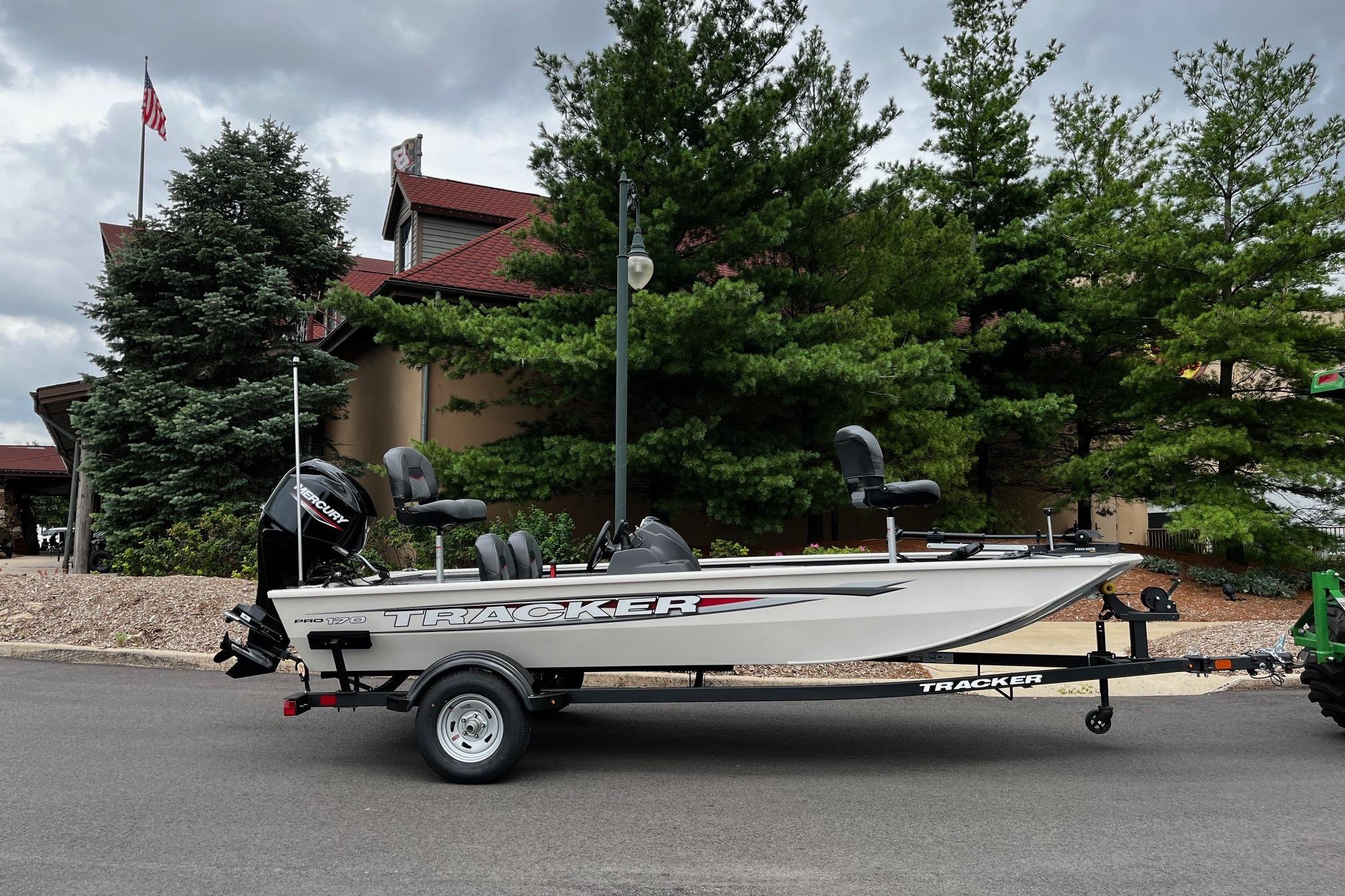 Tracker Pro 170 2026 Tracker Pro 170 boat on trailer, parked near trees and building.