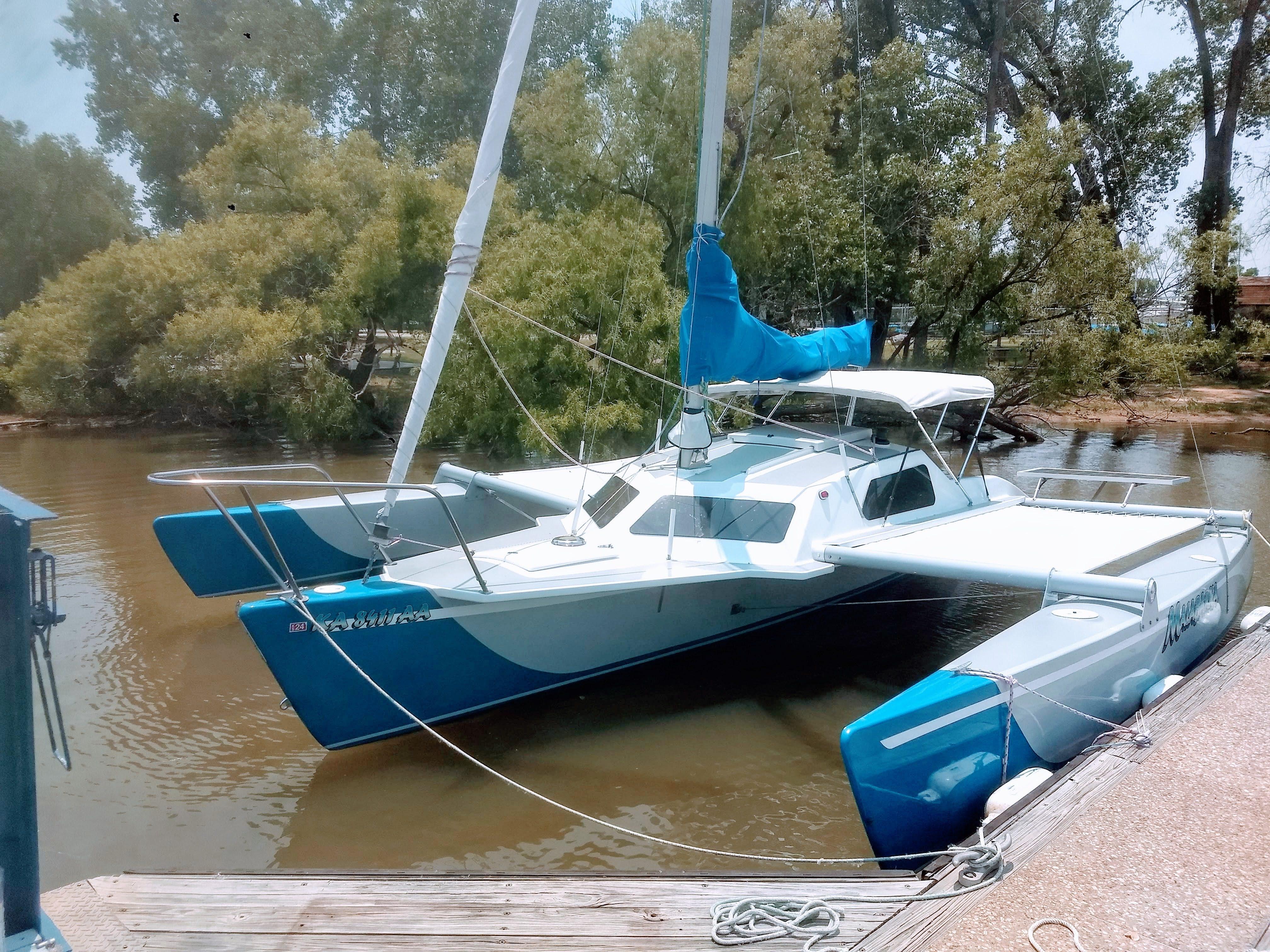 Crowther Buccaneer 24 2017 Crowther Buccaneer 24 trimaran docked on a calm river, surrounded by trees.