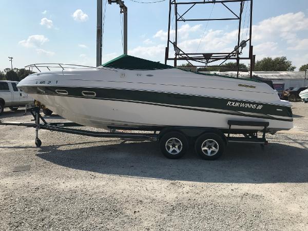 Four Winns 245 Sundowner 2002 Four Winns 245 Sundowner boat on a trailer in a parking lot.