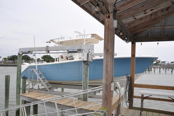 Cobia 301 Center Console 2020 Cobia 301 Center Console boat docked on a lift by a wooden pier.