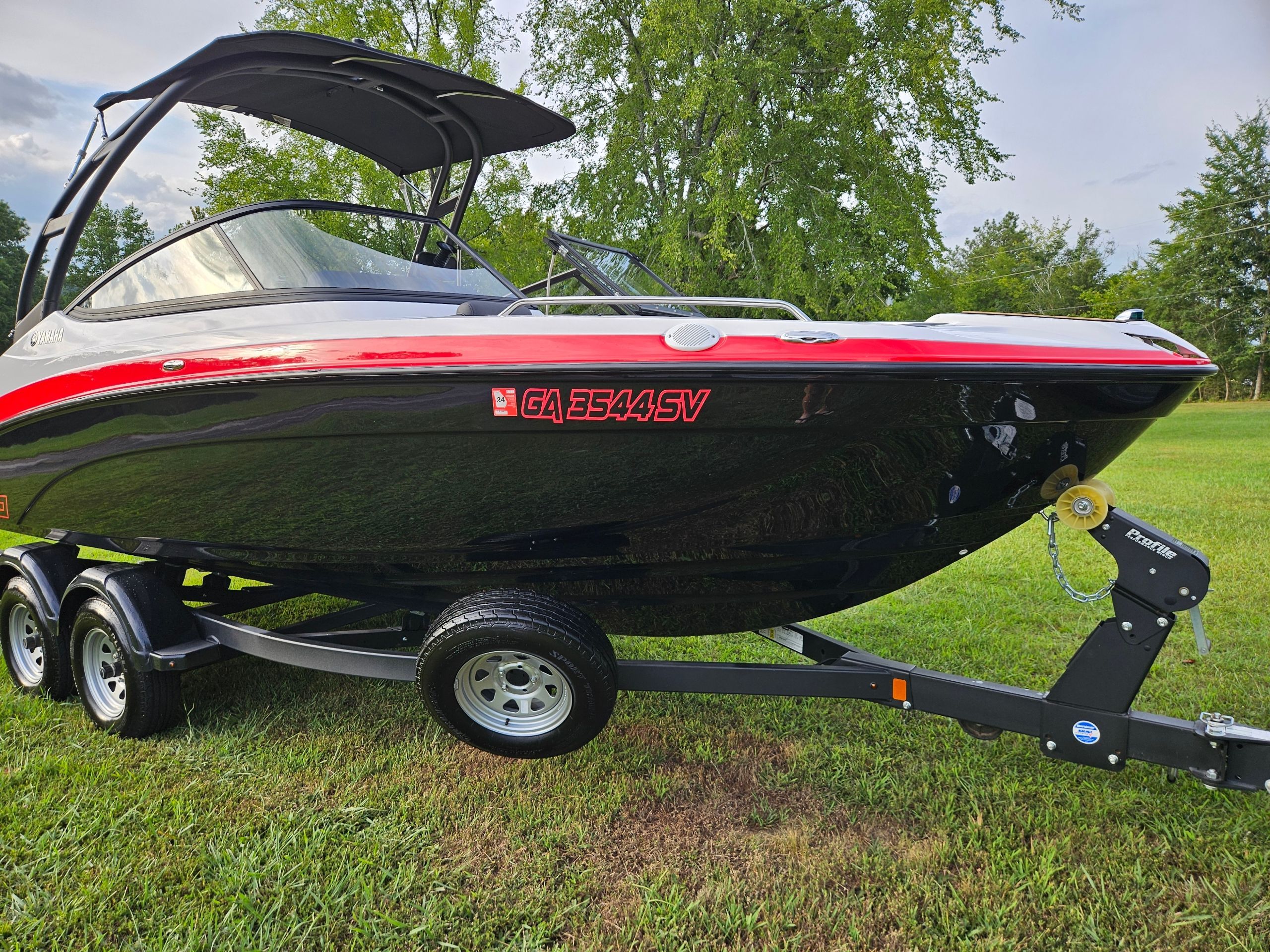 Yamaha Boats AR 210 2021 Yamaha Boats AR 210 on trailer, parked on grass, with trees in the background.