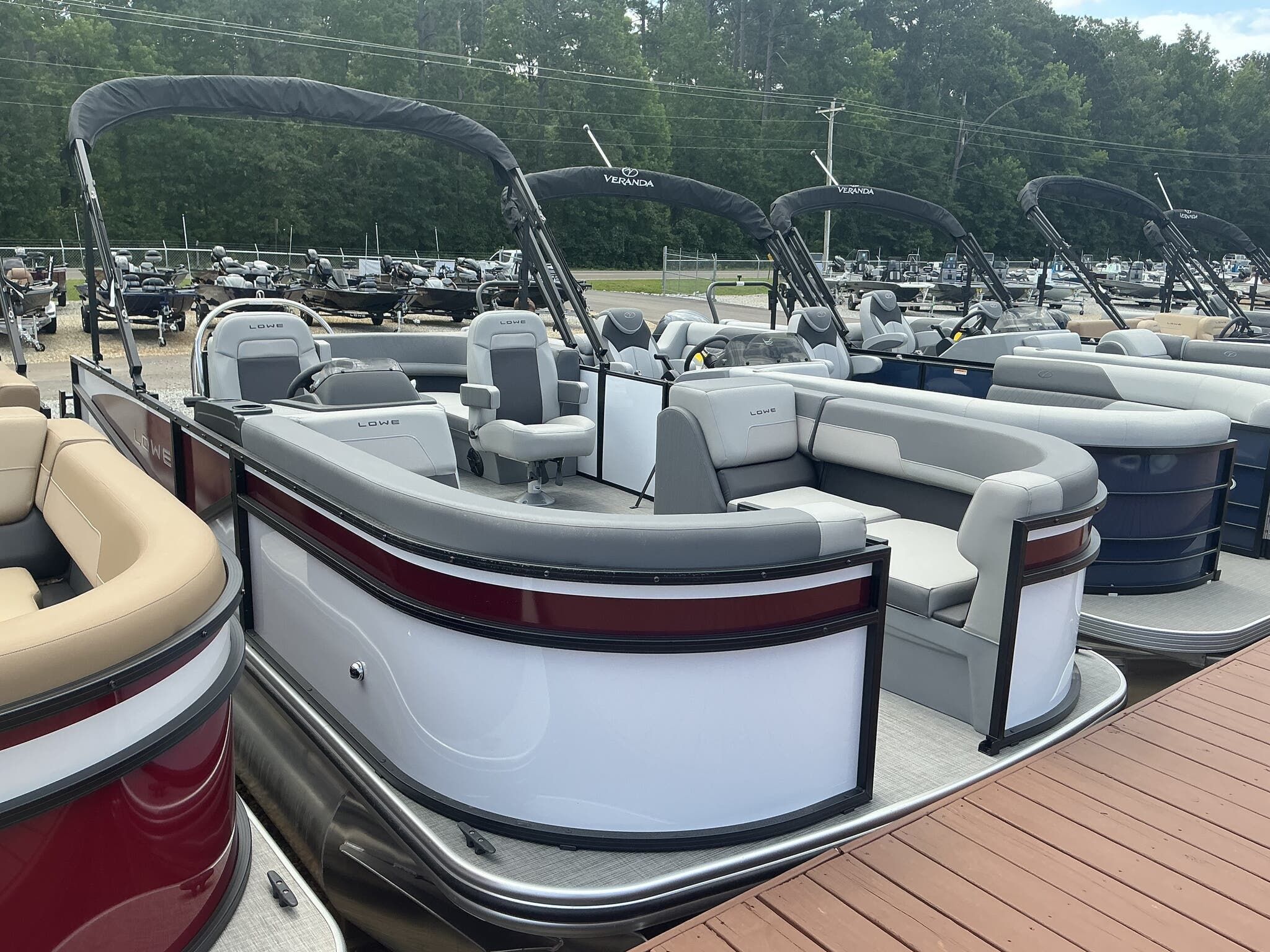 Lowe LS 190 2025 Lowe LS 190 pontoon boat with gray seating, docked alongside similar models.