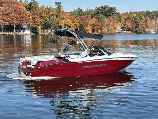 MasterCraft XT23 2023 MasterCraft XT23 boat on a lake with autumn foliage background.