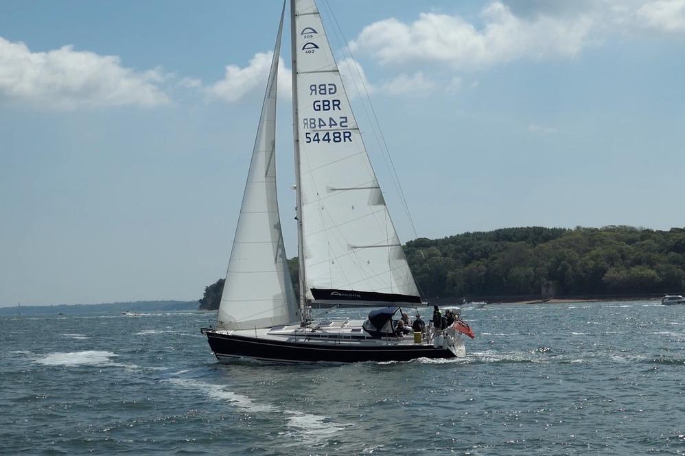 Arcona 400 Sailing yacht Arcona 400, 2003 model, cruising on a sunny day near a forested shoreline.