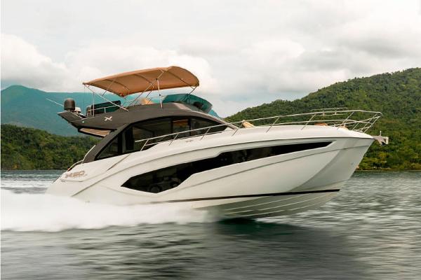 NX Boats 50 Invictus Fly 2025 NX Boats 50 Invictus Fly cruising on water, surrounded by lush green hills.